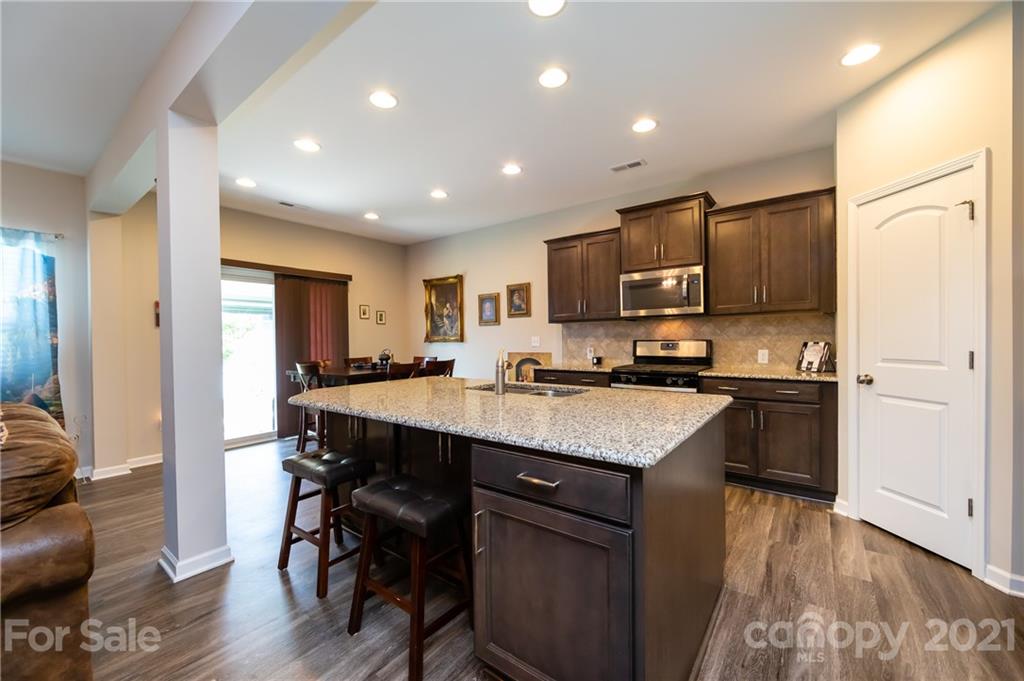 4822 Abendego Road Charlotte, NC 28213 - Photo 12 of 48 a kitchen with kitchen island granite countertop wooden floors and refrigerator