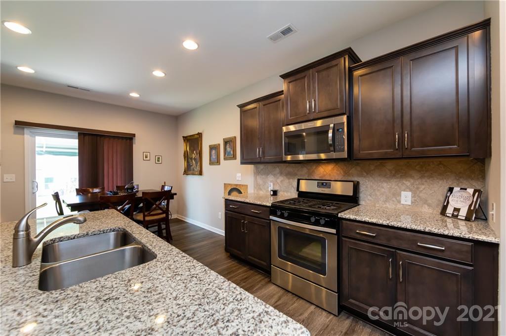 4822 Abendego Road Charlotte, NC 28213 - Photo 13 of 48 a kitchen with granite countertop wooden cabinets stainless steel appliances and a sink