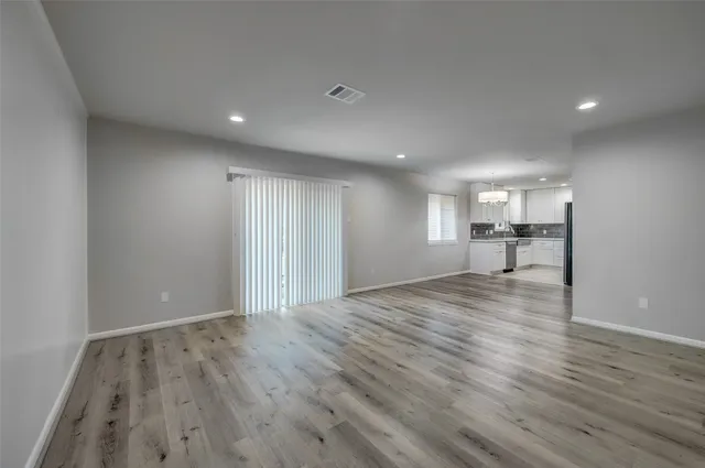 a view of empty room with wooden floor and a window