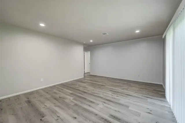 an empty room with wooden floor and entrance