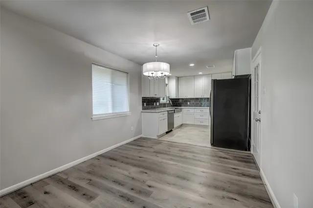 a kitchen with granite countertop a refrigerator and a wooden floor