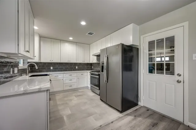 a kitchen with stainless steel appliances granite countertop a refrigerator a stove and a sink