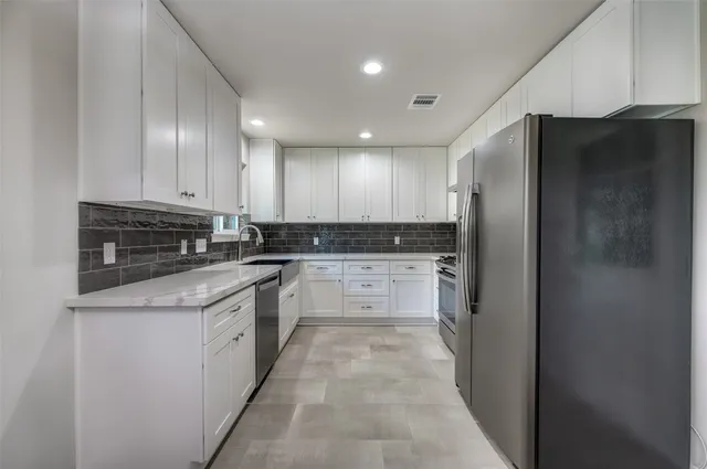 a large kitchen with stainless steel appliances granite countertop a refrigerator and a stove top oven