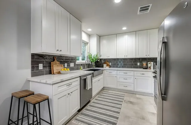 a kitchen with granite countertop a stove a sink and a refrigerator