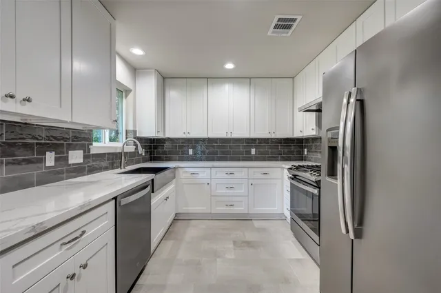 a kitchen with stainless steel appliances granite countertop a stove a sink and a refrigerator