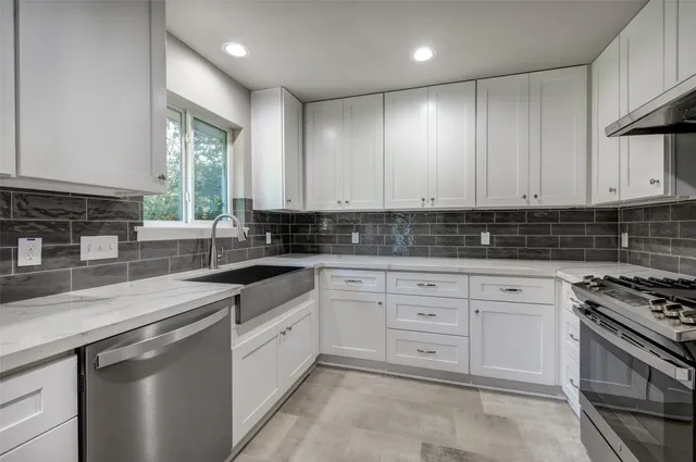 a kitchen with stainless steel appliances granite countertop a sink a stove and cabinets