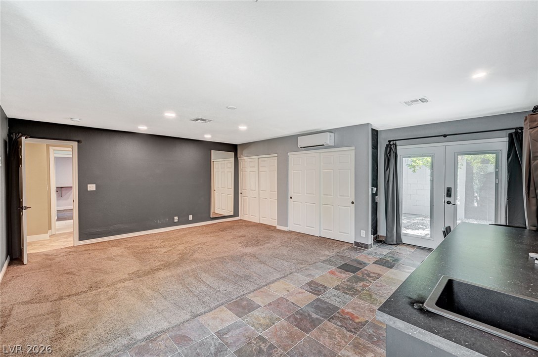 4153 Woodcrest Road Las Vegas, NV 89121 - Photo 29 of 58 A spacious room offers dual flooring, with plush carpeting transitioning to elegant tile near outdoor access.