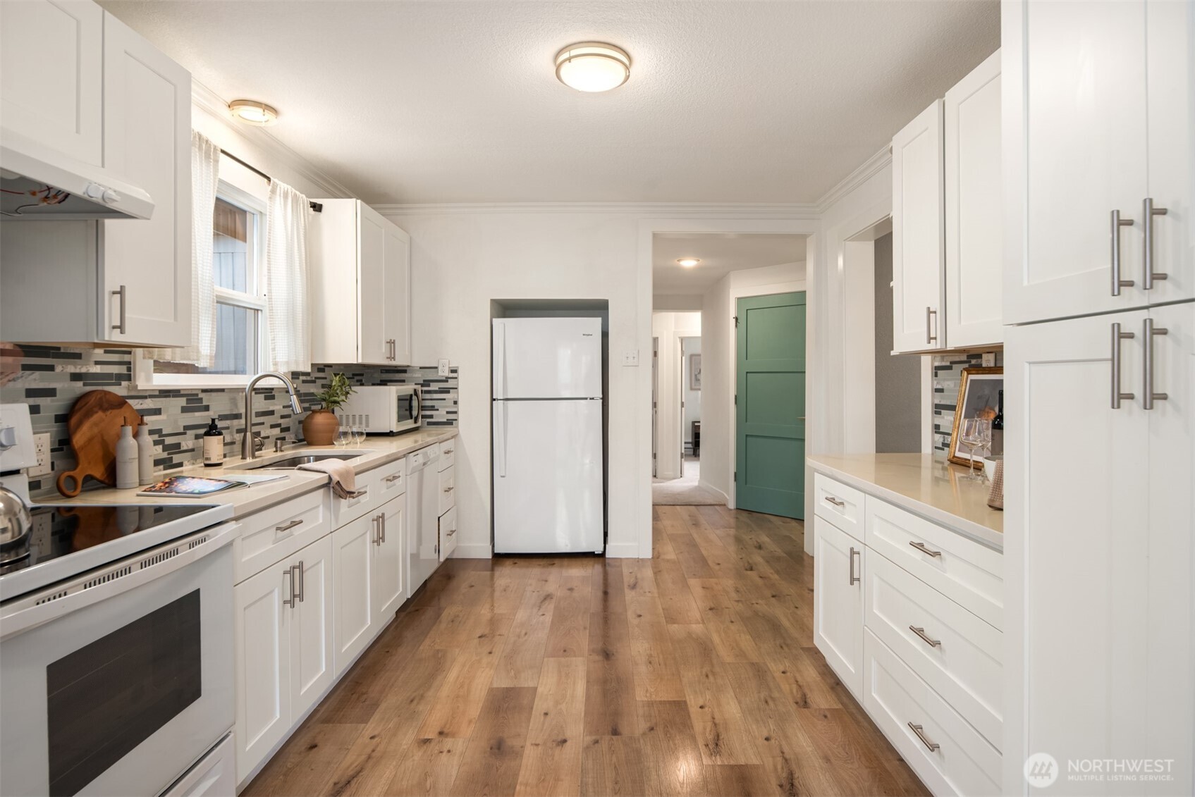 5115 South Roxbury Street Seattle, WA 98118 - Photo 11 of 29 a kitchen with stainless steel appliances white cabinets and wooden floors