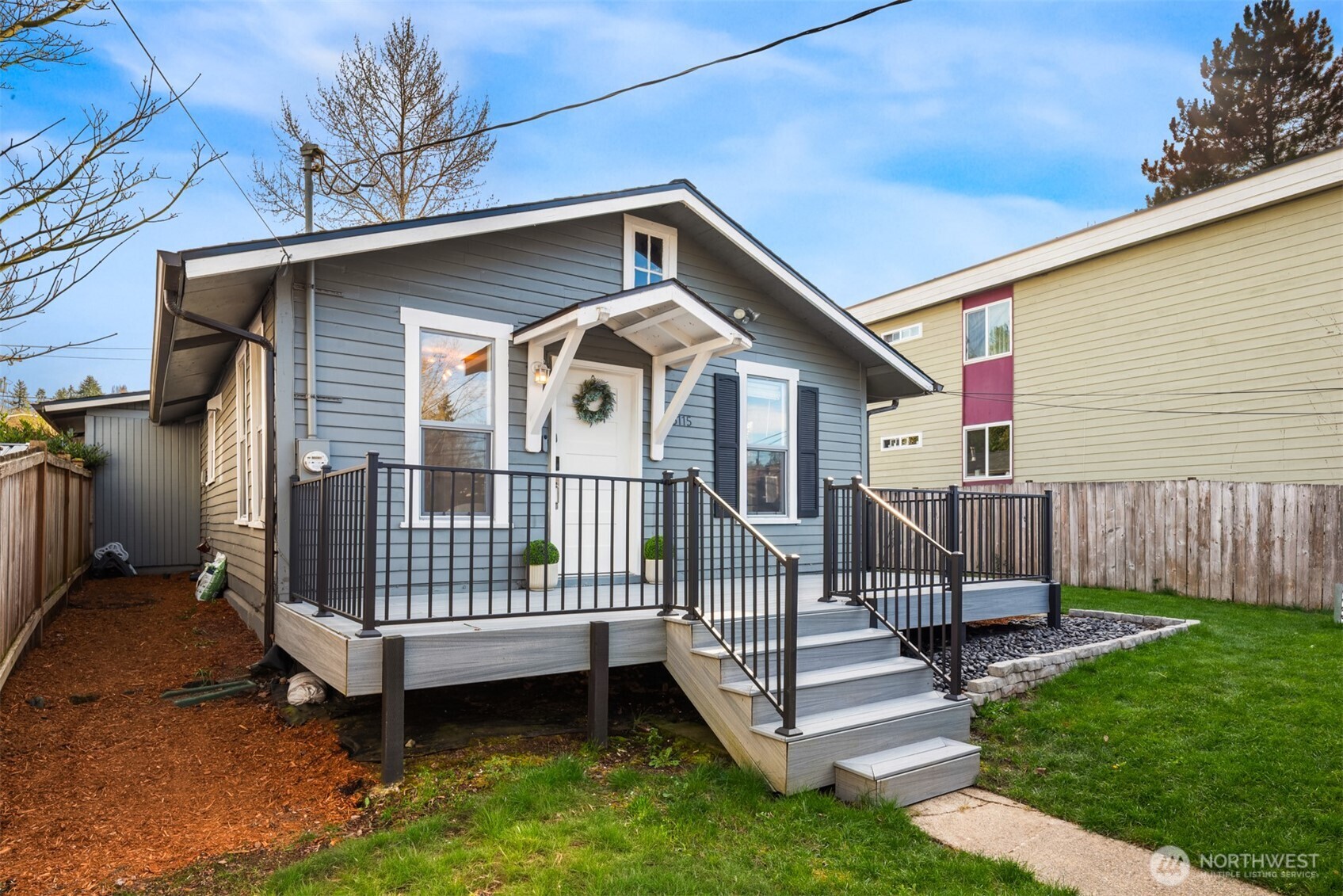 5115 South Roxbury Street Seattle, WA 98118 - Photo 29 of 29 a view of a wooden house with a small yard and wooden fence