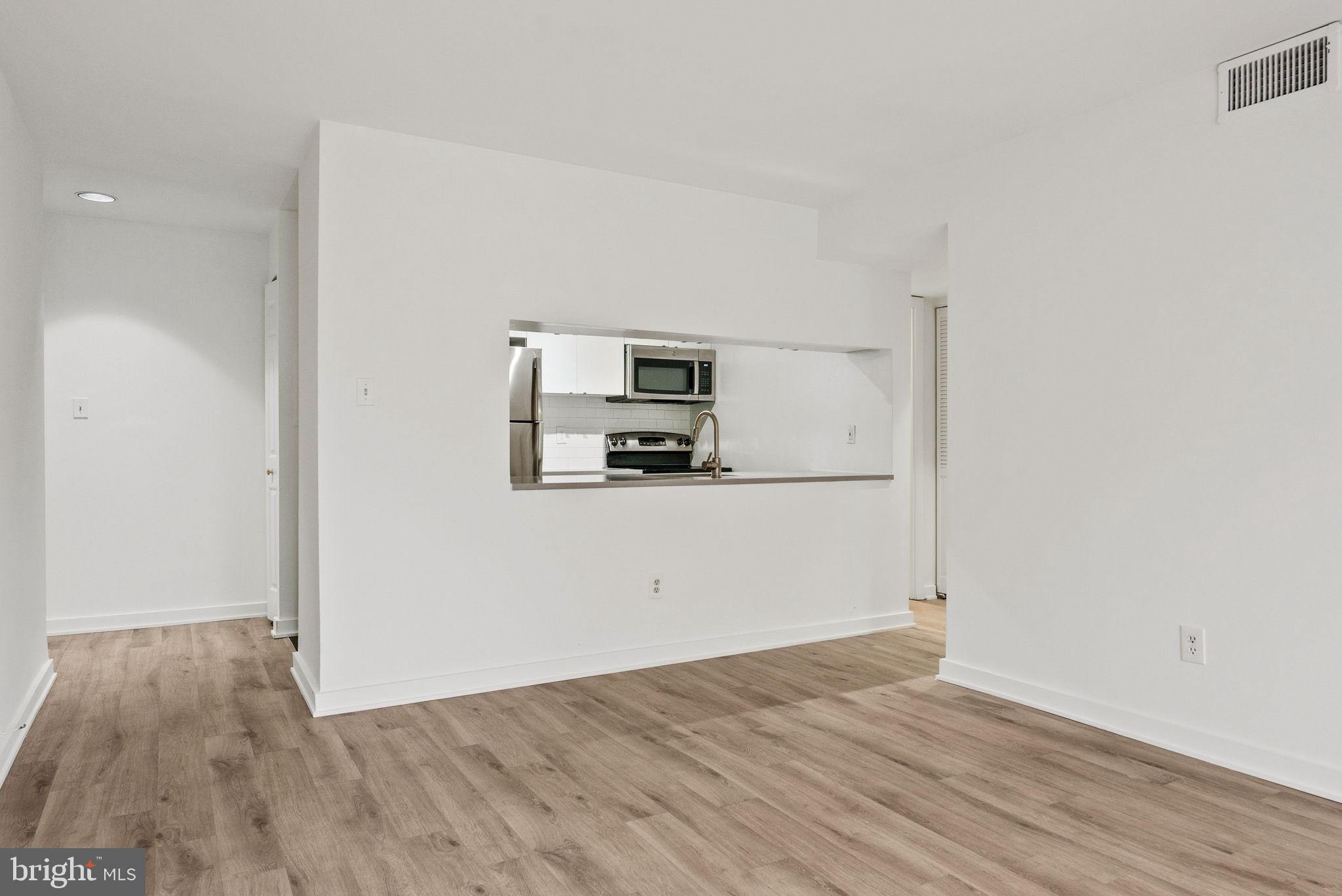 601 24th Street Northwest, Unit 306 Washington, DC 20037 - Photo 11 of 34 a view of a refrigerator in kitchen and an empty room with wooden floor