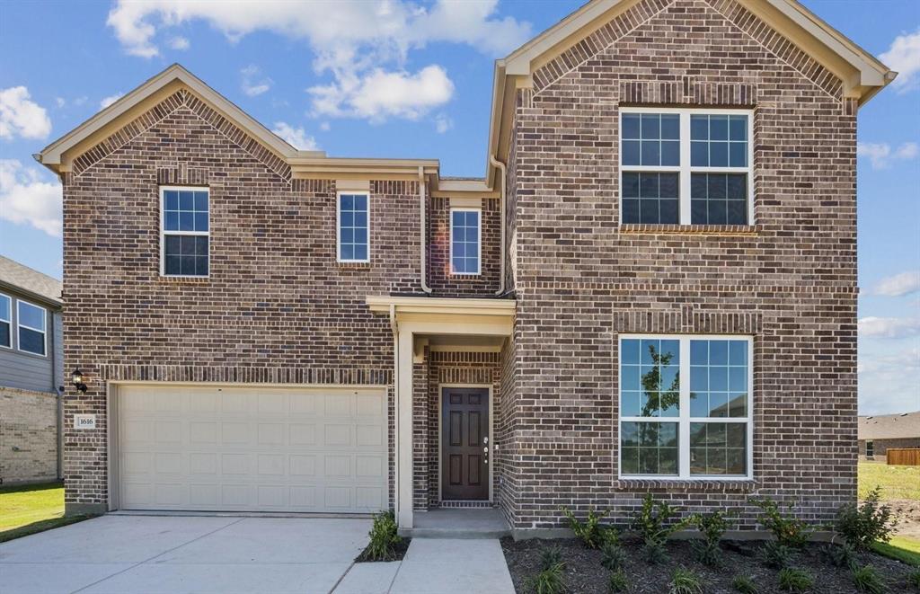 Traditional-style home with brick siding, driveway, and an attached garage