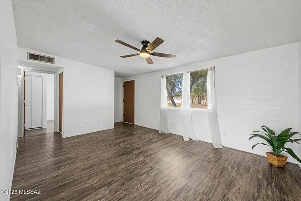a view of an empty room with a window and wooden floor