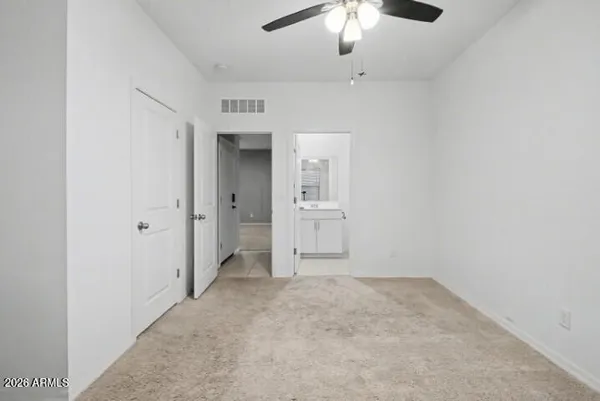 an empty room with chandelier fan and windows