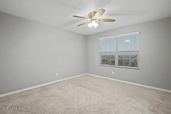 an empty room with a chandelier fan and windows