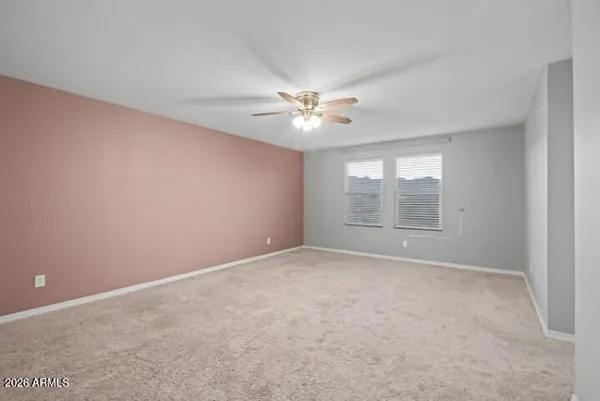 a view of an empty room with window and chandelier fan
