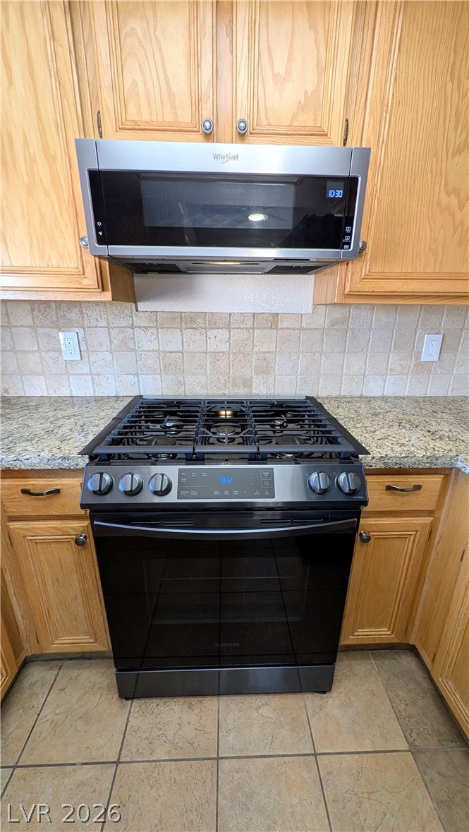 1685 Strasbourg Way, Unit 1685 Henderson, NV 89014 - Photo 13 of 22 Kitchen with stainless steel appliances, light stone countertops, tasteful backsplash, and wood finish cabinets