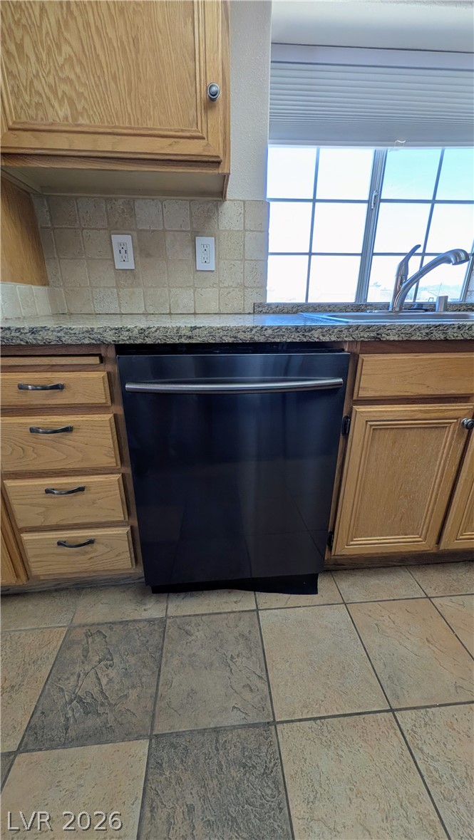 1685 Strasbourg Way, Unit 1685 Henderson, NV 89014 - Photo 14 of 22 Kitchen view of dishwashing machine, wood finish cabinetry, dark stone countertops, and backsplash