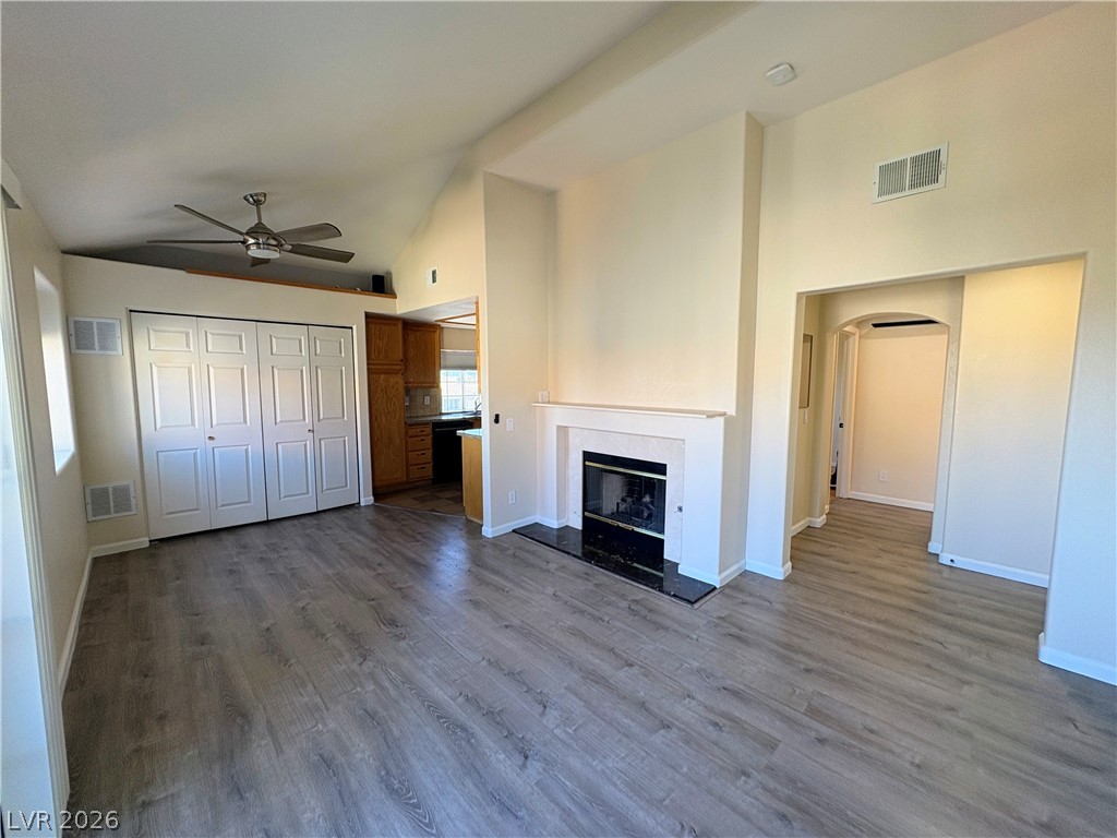 1685 Strasbourg Way, Unit 1685 Henderson, NV 89014 - Photo 7 of 22 Unfurnished living room with lofted ceiling, a ceiling fan, dark wood finished floors, a glass covered fireplace, and arched walkways