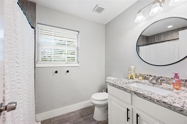 a bathroom with a granite countertop toilet a sink and a mirror