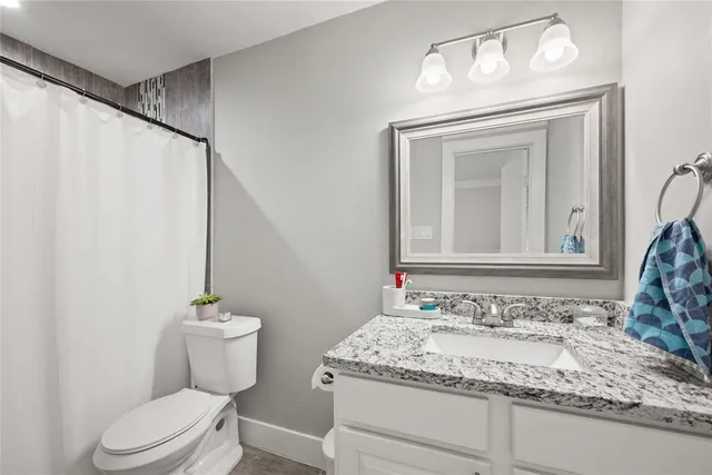 a bathroom with a granite countertop sink a toilet and a mirror