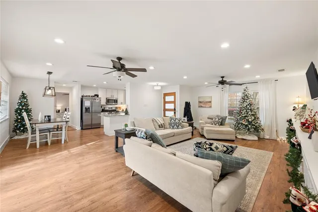 a living room with furniture kitchen view and a wooden floor