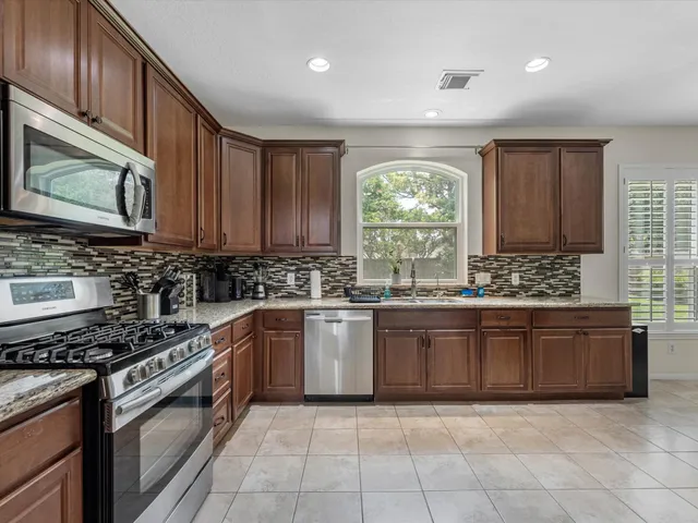 a large kitchen with stainless steel appliances granite countertop a stove a sink and a microwave