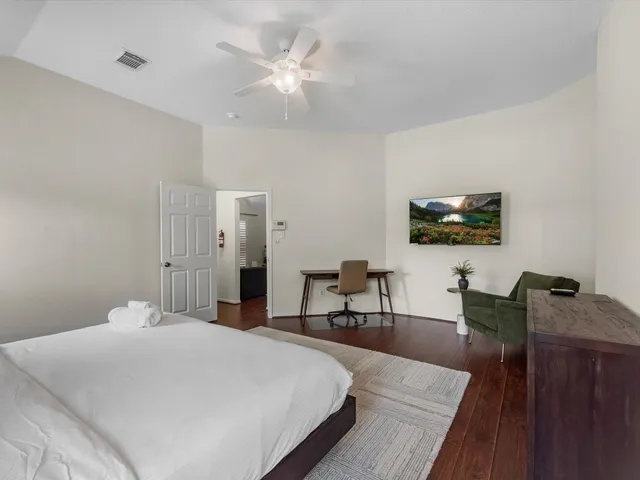 a bedroom with a bed a table and chair with the wooden floor