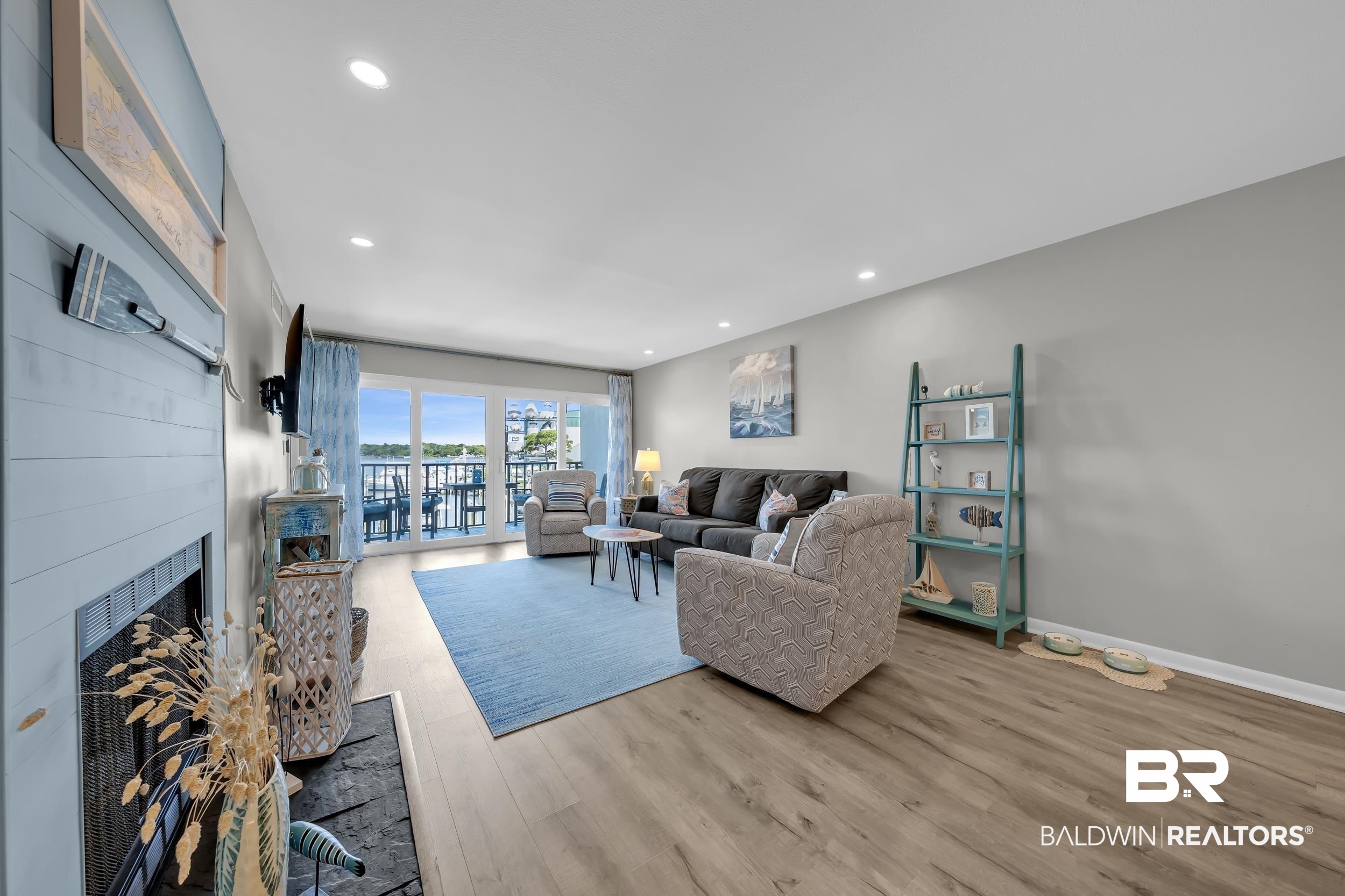 14100 River Road, Unit 211 Pensacola, FL 32507 - Photo 12 of 56 Living area featuring wood-finish flooring, recessed lighting, a fireplace with a light blue shiplap facade, and a full-width glass sliding door opening to a balcony