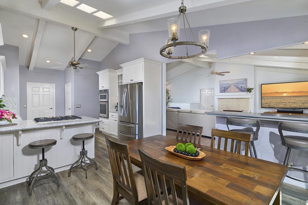 4235 Harrison Street Carlsbad, CA 92008 - Photo 7 of 55 a kitchen with stainless steel appliances kitchen island granite countertop a dining table chairs and white cabinets