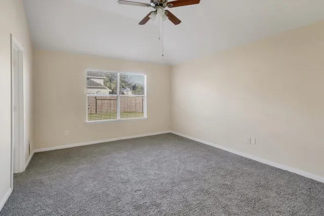 an empty room with a window and a ceiling fan