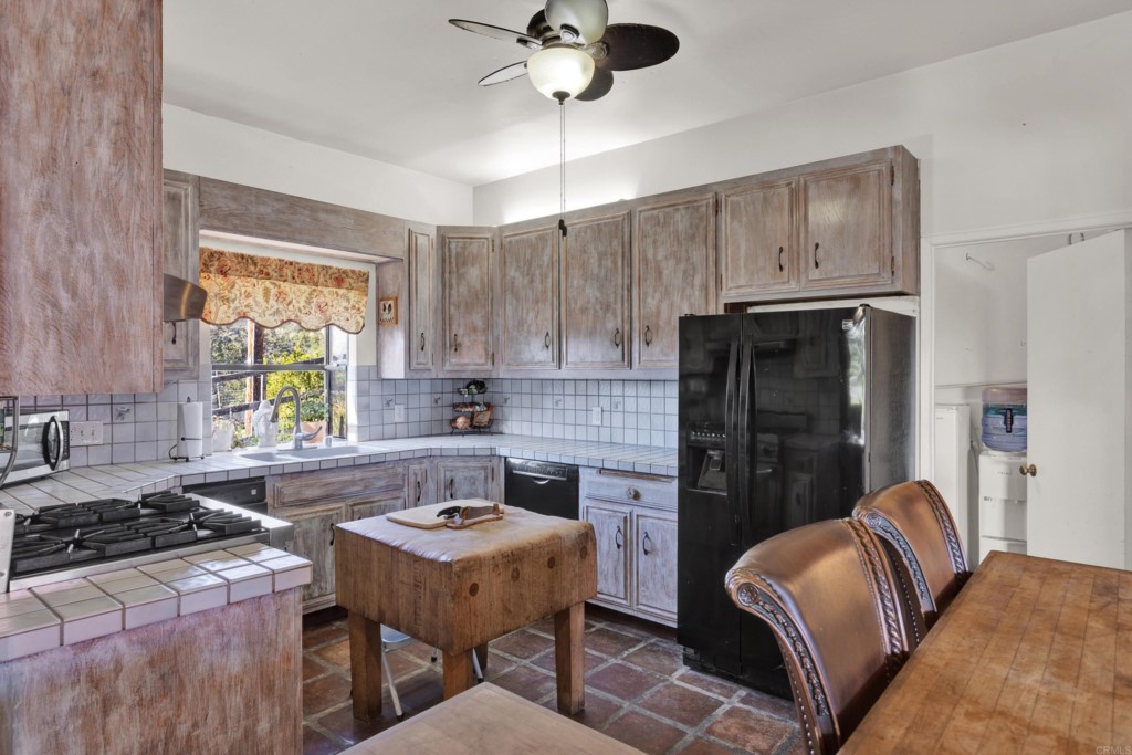15866 Lyons Valley Road Jamul, CA 91935 - Photo 16 of 56 a kitchen with stainless steel appliances granite countertop a refrigerator a stove a sink dishwasher a dining table and chairs with wooden floor
