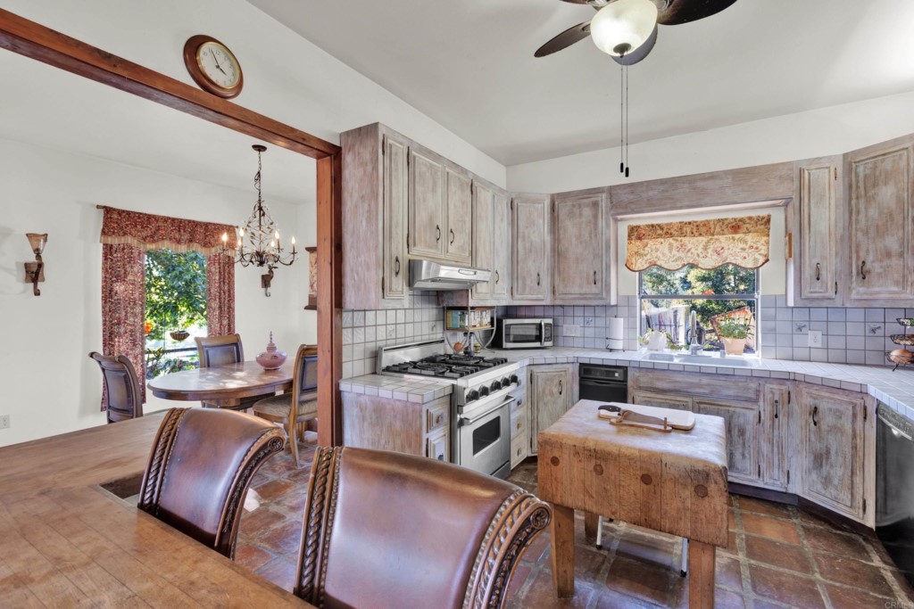 15866 Lyons Valley Road Jamul, CA 91935 - Photo 17 of 56 a kitchen with stainless steel appliances granite countertop a stove a sink dishwasher a dining table and chairs with wooden floor