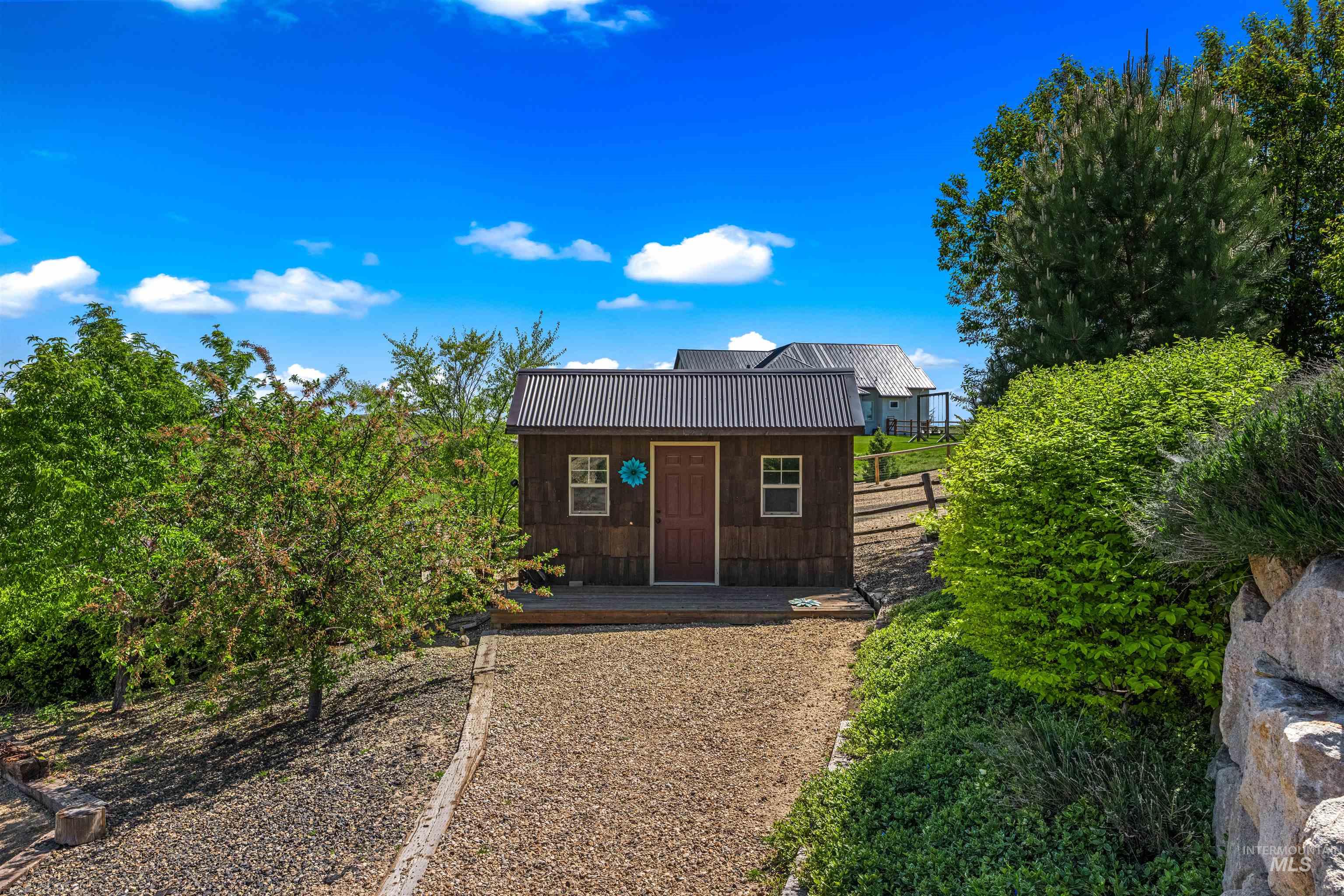 7521 North Grand Ridge Lane Eagle, ID 83616 - Photo 49 of 50 Wood-sided outbuilding featuring a metal roof, single entry door, and two windows