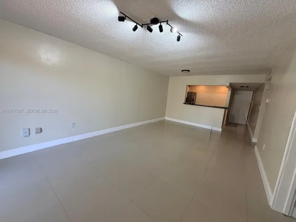 a view of a room with a hanging light and hardwood floor