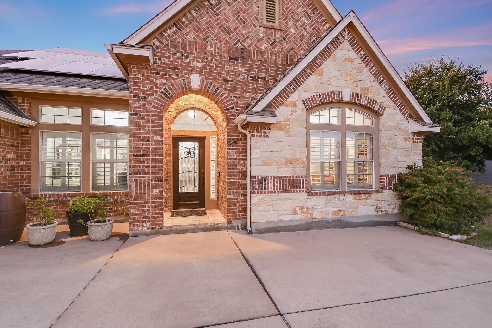 300 Wesley Ridge Drive Spicewood, TX 78669 - Photo 4 of 40 This charming entrance showcases the blend of brick and stone accents, welcoming guests through an elegant front door framed by arched windows.