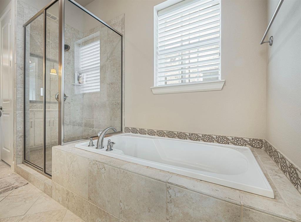 5001 Meridian Lane, Unit 2103 Addison, TX 75001 - Photo 17 of 26 Soaking tub with decorative tile surround, complemented by a glass-enclosed shower with tile walls