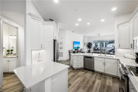 a large kitchen with kitchen island a sink a stove a refrigerator and white cabinets