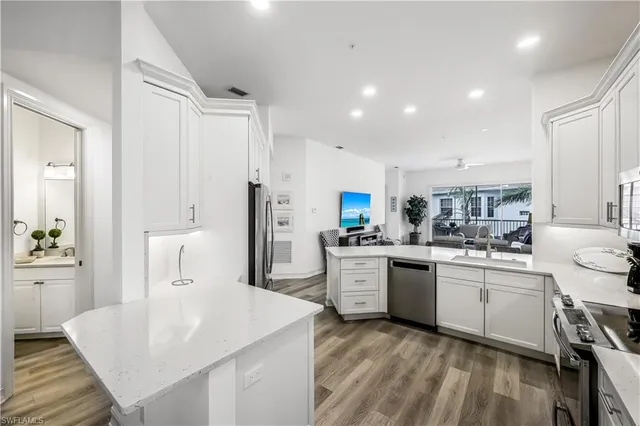 a large kitchen with kitchen island a sink a stove a refrigerator and white cabinets