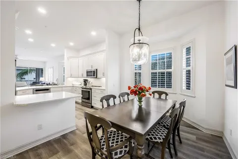 a kitchen with stainless steel appliances a dining table chairs and white cabinets