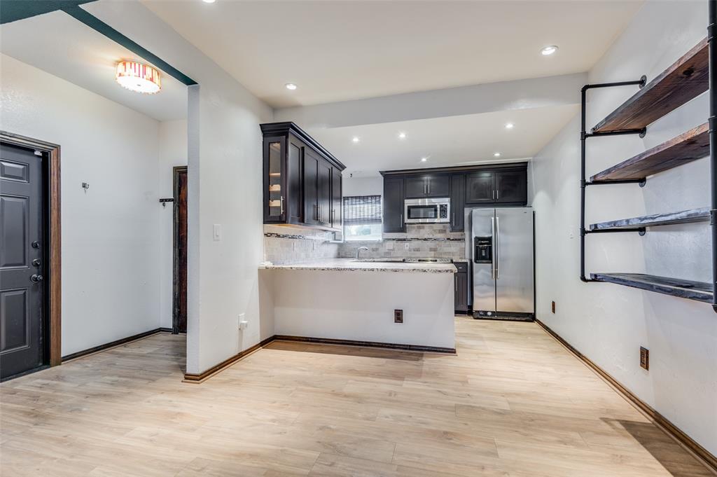 2749 Buna Drive Dallas, TX 75211 - Photo 4 of 12 Kitchen featuring appliances with stainless steel finishes, light stone countertops, light wood-style flooring, a peninsula, and recessed lighting