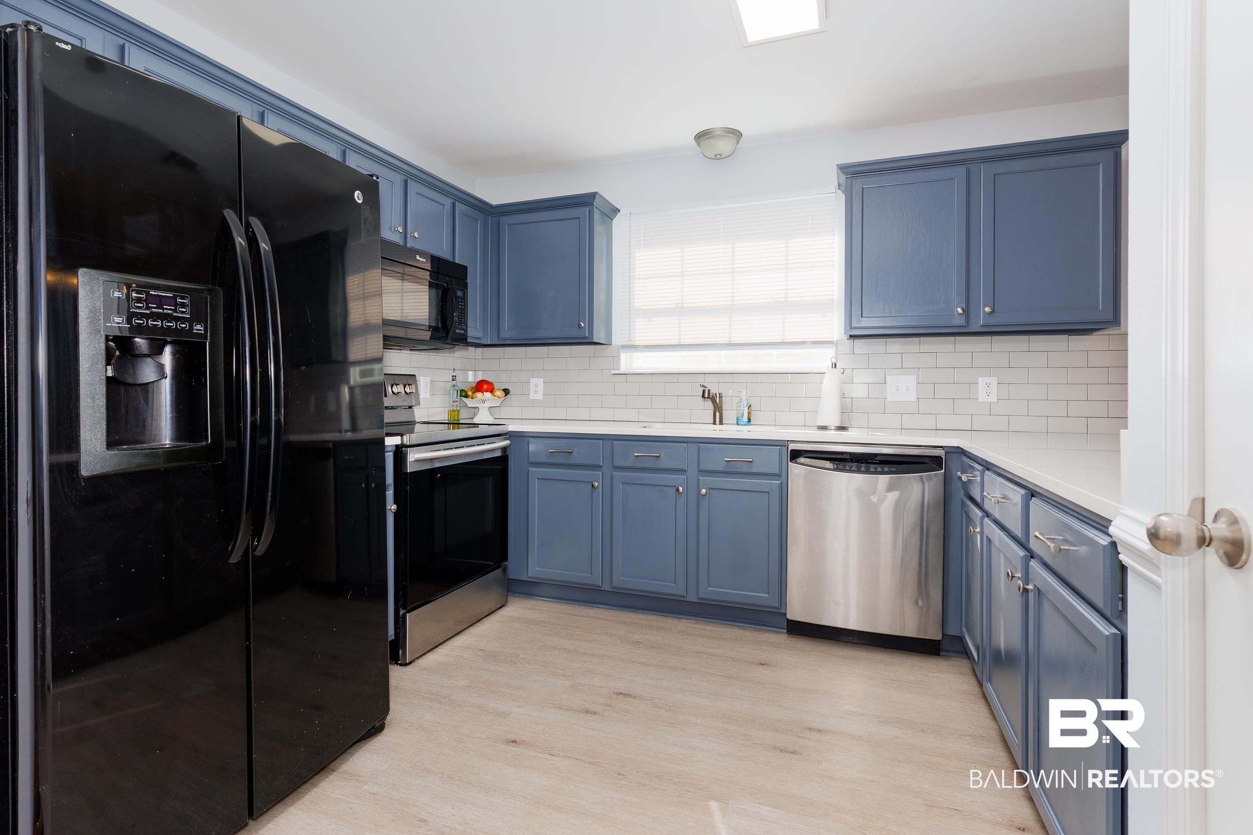 16227 Zenith Drive Loxley, AL 36551 - Photo 4 of 23 Kitchen with black appliances, blue cabinetry, light wood-style floors, backsplash, and light stone counters