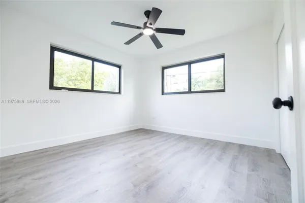 an empty room with wooden floor and windows