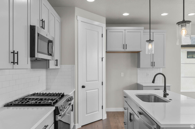1567 North 3250 West Provo, UT 84601 - Photo 12 of 22 Contemporary kitchen featuring white shaker cabinetry with matte black hardware, white subway tile backsplash, stainless steel appliances, and a kitchen island with an undermount sink and matte black faucet