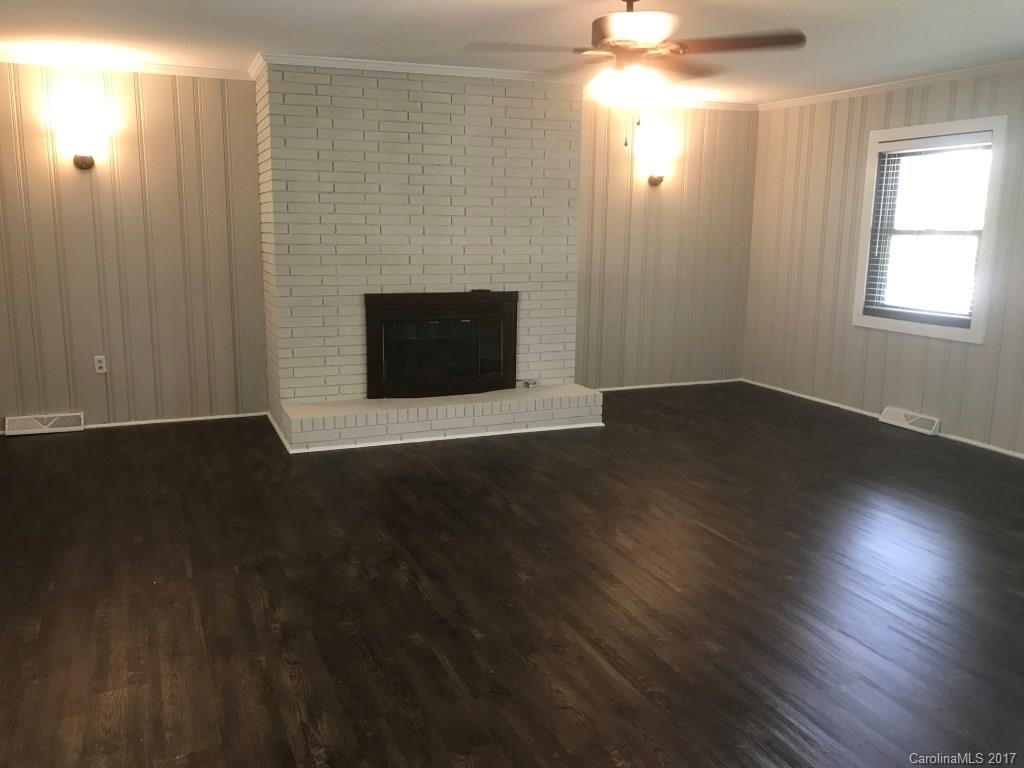 6561 Morehead Road Harrisburg, NC 28075 - Photo 4 of 24 an empty room with wooden floor fireplace and windows