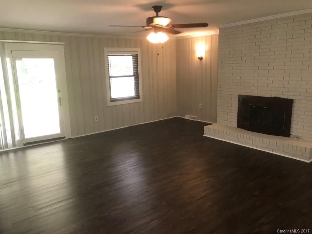 6561 Morehead Road Harrisburg, NC 28075 - Photo 5 of 24 an empty room with wooden floor fireplace and windows