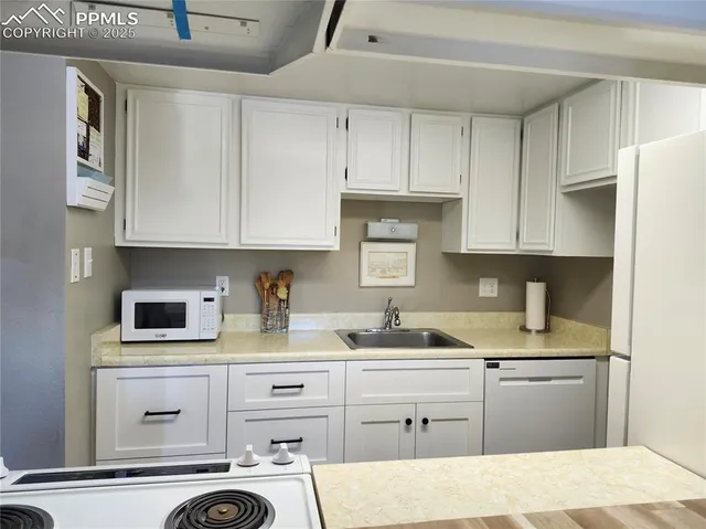a kitchen with white cabinets and appliances
