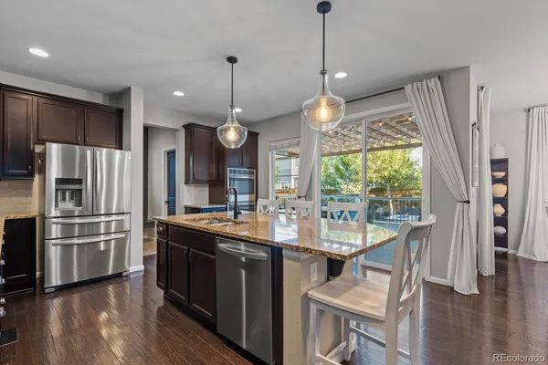 a kitchen with stainless steel appliances granite countertop a sink a stove and a refrigerator