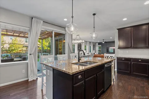 a kitchen with stainless steel appliances granite countertop a sink a stove and a wooden floors