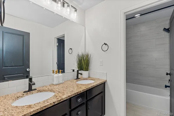 a bathroom with a granite countertop sink and a mirror a bathtub