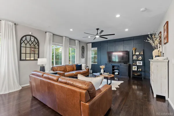 a living room with furniture a large window and wooden floor